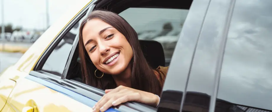 Mujer feliz mirando por la ventana del taxi